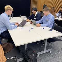 three students sit at table deep in thought
