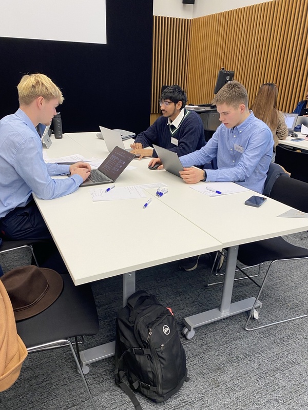 three students sit at table deep in thought